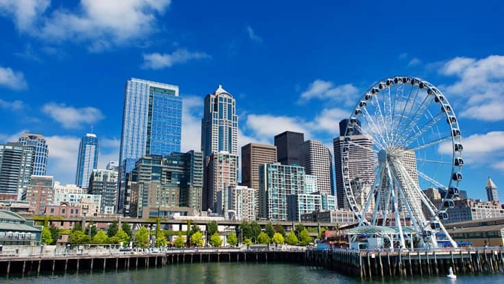 See the day time skyline of  Seattles' Great Wheel in Elliot Bay on an overnight hotel stay with Oceania Cruises.